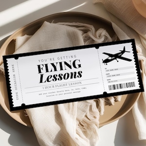 May include: A black and white gift voucher for flying lessons. The voucher features the text "YOU'RE GETTING FLYING Lessons" and "1 HOUR FLIGHT LESSON". It includes a small airplane silhouette and space for details.
