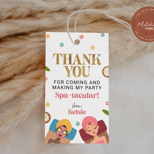 Op de afbeelding: Witte bedankkaart met gouden tekst die "Bedankt" en "Spa-taculair!" zegt, met illustraties van twee vrouwen die gezichtsbehandelingen krijgen. De tekst zegt ook "Voor je komst en het maken van mijn feestje" en "liefs, Kelsie".