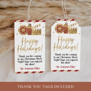 Puede incluir: Dos etiquetas de regalo a rayas rojas y blancas con detalles dorados. Las etiquetas presentan un carrete de pel&iacute;cula, un cubo de palomitas de ma&iacute;z y una claqueta. El texto en las etiquetas dice "&iexcl;Felices Fiestas!" y "&iexcl;Gracias por venir a nuestra Noche de Cine Navide&ntilde;a! &iexcl;Espero que hayas disfrutado del espect&aacute;culo! La familia Anderson."