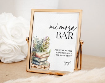 Puede incluir: Un letrero con marco dorado con las palabras "mimosa BAR" en escritura negra. El letrero incluye el texto "Vierta el champán, agregue un poco de jugo, cubra con fruta, ¡disfrute!" y una ilustración de acuarela de libros y follaje.