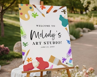 Può includere: Un cavalletto di legno espone un cartello bianco con la scritta "WELCOME TO Melody's ART STUDIO!" e la data "JUNE 23, 20XX." Il cartello è decorato con schizzi di vernice colorati, pennelli e tubetti di vernice.