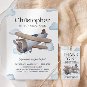 May include: Blue and brown airplane illustration on a white card with blue clouds. The card says "Christopher is turning one" and includes details for a birthday party. A matching thank you tag with the same airplane illustration says "Thank you for flying by! I hope you had fun! Christopher."