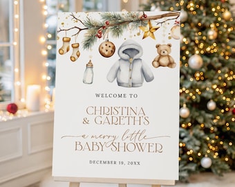 May include: A white rectangular sign featuring watercolour illustrations of pine branches, red berries, a gold star, two stockings, a baby bottle, a hooded jacket, and a teddy bear. Text reads: WELCOME TO CHRISTINA & GARETH'S a merry little BABY SHOWER DECEMBER 19, 20XX.