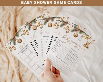 May include: A set of white paper baby shower game cards featuring a Christmas-themed border with pine branches, ornaments, stockings, and a teddy bear. The cards include printed text such as Baby Predictions & Advice, with blank lines for writing.