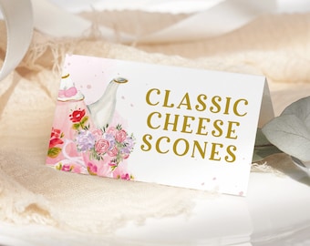 Puede incluir: Una tarjeta blanca con acentos de acuarela rosa y una ilustración de tetera dorada. La tarjeta dice "CLASSIC CHEESE SCONES".