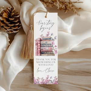 Op de afbeelding: Een witte bladwijzer met een stapel antieke boeken, roze bloemen en de tekst "Our story begins! Thank you for showering us with love! Love, Claire".