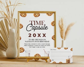 Op de afbeelding: Een wit bord met een gouden lijst en bruine tekst die "TIME Capsule 20XX TO BE OPENED ON NATHAN'S 18TH BIRTHDAY Please take a moment to write a sweet message. Make a prediction or share your hopes and wishes. Don't forget to sign your name." luidt.