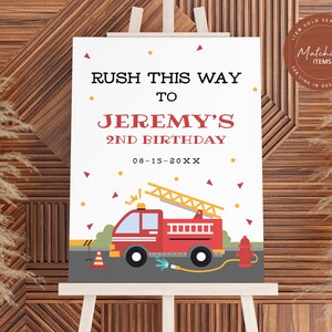 May include: A white sign with red and yellow accents, announcing "RUSH THIS WAY TO JEREMY'S 2ND BIRTHDAY 08-15-20XX". The sign features a cartoon red fire truck with a ladder, a yellow fire hydrant, and a yellow and orange traffic cone.