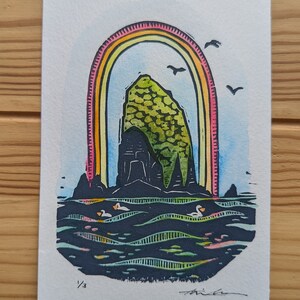 Könnte beinhalten: Ein farbenfroher Kunstdruck, der eine Felsformation unter einem Regenbogen zeigt, mit Vögeln und Enten auf dem Wasser. Der Druck ist mit 1/3 nummeriert und signiert. Das Kunstwerk hat eine lebendige Farbpalette.