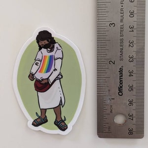 Puede incluir: Una pegatina de una persona de dibujos animados que lleva una camisa blanca con un arco&iacute;ris y una bolsa marr&oacute;n. La persona est&aacute; de pie sobre un fondo verde.
