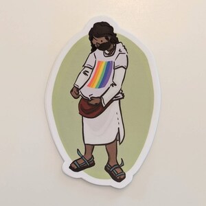 Puede incluir: Una ilustraci&oacute;n de dibujos animados de una persona que lleva una t&uacute;nica blanca y sandalias, con una camiseta arco&iacute;ris debajo. La persona est&aacute; de pie sobre un fondo verde.