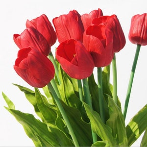 May include: A bouquet of red artificial tulips with green leaves.