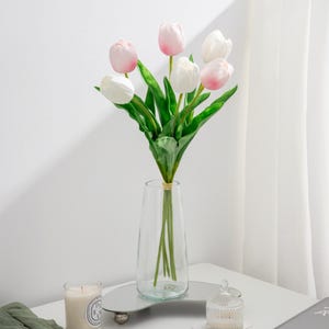 May include: A bouquet of artificial tulips in a clear glass vase. The tulips are a mix of white and pink.