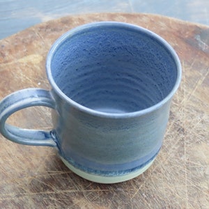 Hand thrown smooth white stoneware mug made in Scotland by Jenny Finch with gorgeous blue grey glaze. 230ml 8cm wide x 9xcm tall.