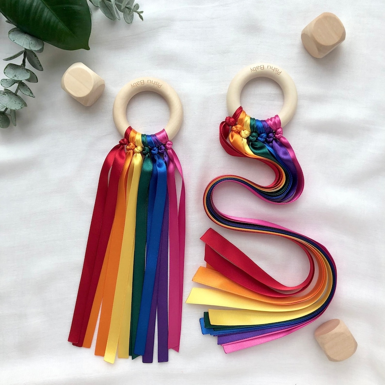 A smooth wooden ring with knotted ribbons used as a gym sensory toy for babies. It is available in two different ribbon lengths; 21cm and 42cm. You can also choose from five different colours: rainbow, pastel rainbow, monochrome, pink, or blue.