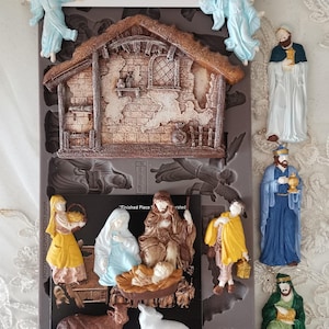 May include: A mold for creating a Holy Night Nativity scene, featuring a stable, angels, and figures of Mary, Joseph, and the baby Jesus. The mold is 5" x 10" and includes the text "DECOR MOULDS" and "HOLY NIGHT NATIVITY".