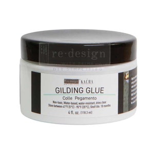 May include: A white jar of gilding glue with a black lid. The label reads "GILDING GLUE" and "4 fl. oz. (118.3 ml)." The glue is water-based, non-toxic, and water-resistant. The product is from "re-design with Prima."
