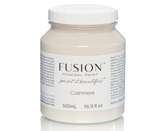 May include: A jar of Fusion Mineral Paint in the color "Cashmere." The jar is filled with a creamy, off-white paint. The label includes the brand name, "Fusion Mineral Paint," and the text "paint it beautiful." The jar contains 500mL or 16.9 fl oz.