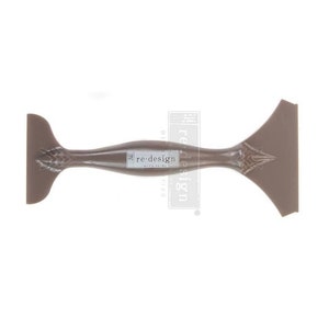 May include: A brown plastic tool with a handle and a flat, angled blade. The tool is designed for spreading paint or other materials. The tool is labeled "re-design with prima"