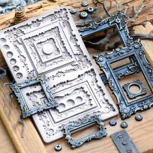 May include: A large rectangular silicone mold featuring intricate embossed scrollwork and geometric patterns, accompanied by several dark metallic-finished resin frames and small decorative accents with ornate floral and leaf detailing.