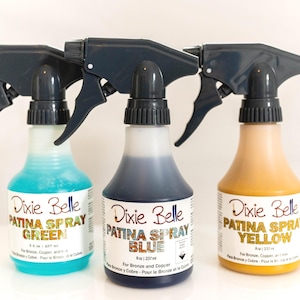 May include: Three spray bottles of Dixie Belle Patina Spray in green, blue, and yellow. Each bottle has a black spray nozzle and a label with the product name. The bottles are 8 oz / 237 ml.