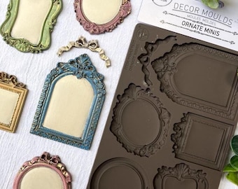 Puede incluir: Una colección de mini moldes de marcos ornamentados y marcos acabados en varios colores. El molde de silicona presenta diferentes formas de marco. Los marcos acabados incluyen dorado, verde, rosa y azul, con centros de color crema. El embalaje dice "DECOR MOULDS ORNATE MINIS."
