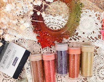 May include: A set of six clear plastic jars filled with colored pigment powder, labeled Fall Foliage by re-design. The jars contain brown, red, purple, orange, gold, and green powders. Each jar has a matching screw-top lid.