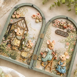 May include: A hinged, arched wooden frame in a muted green finish, featuring a dimensional decoupage scene of anthropomorphic mice gardening. The artwork includes mice in overalls, a greenhouse, floral accents, and a sign reading GARDEN.