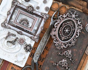 May include: A collection of metallic silver-toned decorative frame components and snowflake-shaped embellishments arranged alongside a pair of vintage metal scissors. The set includes ornate rectangular and oval frame pieces with intricate scrollwork.