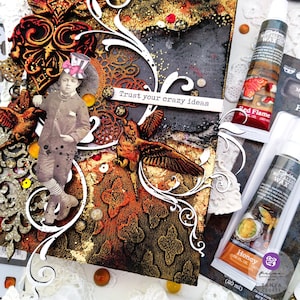 May include: A mixed media art piece with a vintage feel. The piece features a young boy in a top hat, a bird, and a quote that reads "Trust your crazy ideas". The piece is decorated with gold leaf, glitter, and other embellishments. The piece is framed with a white border.