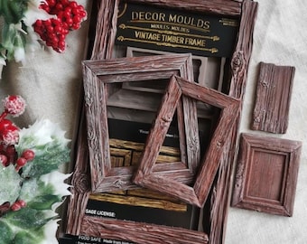 May include: A silicone mold for crafting, labeled Decor Moulds Vintage Timber Frame, featuring recessed designs of rectangular picture frames with a wood grain texture. The mold is dark brown and includes text indicating it is food safe and 5 inches by 8 inches.
