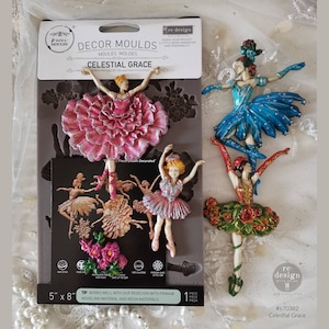 May include: A silicone mold for making ballerina figurines. The mold is 5 inches by 8 inches and includes three different ballerina designs. The ballerinas are shown decorated in pink, blue, and green. The mold is labeled "Celestial Grace" and is part of the "Decor Moulds" line.