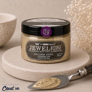 Puede incluir: Un tarro redondo de pl&aacute;stico con pasta de efecto joya Prima Art Extravagance en color Golden Dust. La etiqueta muestra el nombre del producto y un volumen de 100 ml. Una esp&aacute;tula de metal con mango de madera sostiene una porci&oacute;n de pasta dorada.