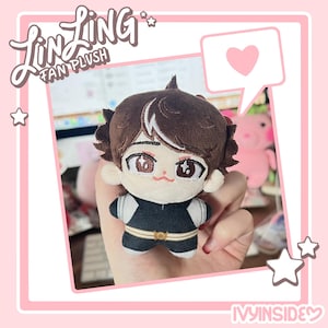 May include: A small plush doll with brown hair and a black and white outfit. The doll has detailed facial features and is held in front of a pink background with the text "Lin Ling Fan Plush" and "Ivy Inside". A pink heart and stars are also visible.