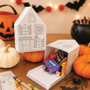 Printable paper house used as a Halloween candy holder after assembling the haunted house paper craft for kids.