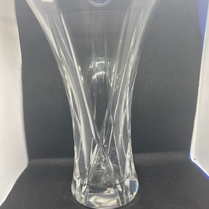 Könnte beinhalten: Eine klare Glasvase mit geschnittenem Kristallmuster. Die Vase hat eine breite Öffnung und einen schmalen Boden. Die Vase ist mit einem blauen und goldenen Aufkleber mit der Aufschrift "Prague Crystal" versehen.