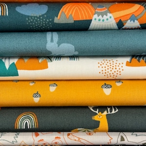 May include: A stack of patterned fabric in various colors. Designs include orange chevron, forest scenes with mountains and rainbows, a bunny, acorns, and a fox. The fabrics are in shades of orange, teal, yellow, and white.
