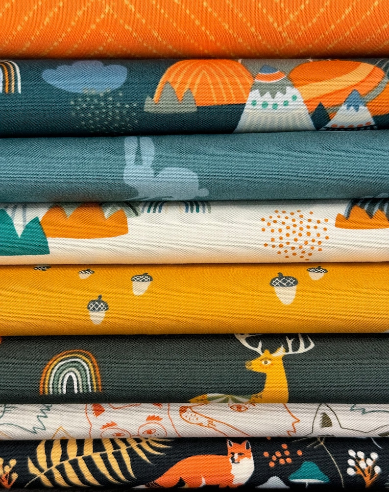 May include: A stack of patterned fabric in various colors. Designs include orange chevron, forest scenes with mountains and rainbows, a bunny, acorns, and a fox. The fabrics are in shades of orange, teal, yellow, and white.