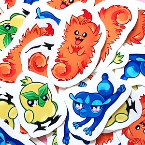 May include: A collection of colorful cartoon stickers featuring various creatures. The stickers showcase a variety of designs, including orange, yellow, and blue characters with expressive faces and unique features. The stickers are on a pink background.