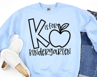 May include: Light blue sweatshirt with black text that reads "K is for Kindergarten" with a black apple graphic.