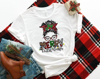 May include: White t-shirt with a graphic of a woman with a messy bun, wearing glasses and a red and green Christmas bow. The text "Merry Postal Worker" is printed below the graphic.