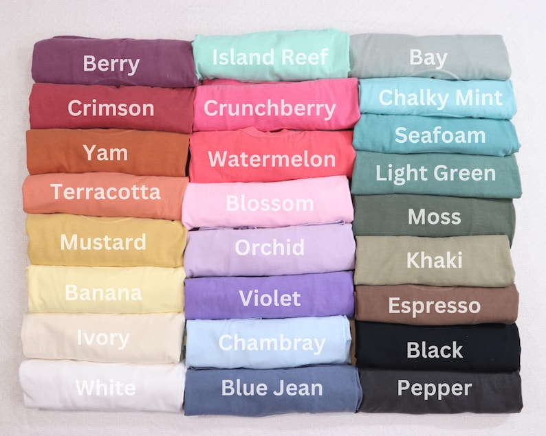 May include: A colour chart of 24 fabric swatches, each folded in half. The swatches are arranged in three columns of eight swatches each. The swatches are labelled with names such as "Berry", "Island Reef", "Bay", "Crimson", "Crunchberry", "Chalky Mint", "Seafoam", "Yam", "Watermelon", "Light Green", "Terracotta", "Blossom", "Moss", "Mustard", "Orchid", "Khaki", "Banana", "Violet", "Espresso", "Ivory", "Chambray", "Black", "White", "Blue Jean", and "Pepper".