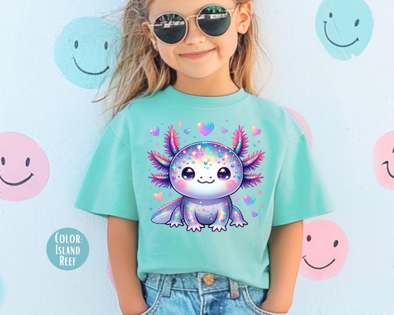 May include: A young person wearing a turquoise blue t-shirt with a colorful cartoon axolotl graphic. The axolotl is surrounded by pink hearts. The text "Color Island Reef" is visible in the lower left corner of the image.