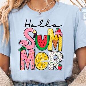 May include: Light blue t-shirt with the text "Hello Summer" in colorful letters. The letters are decorated with a flamingo, watermelon, ice cream cone, lemon, and sprinkles.