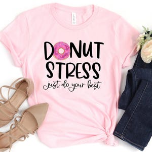 May include: Pink t-shirt with the text "Donut Stress Just Do Your Best" and a pink donut with sprinkles graphic.