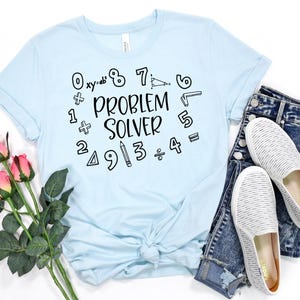 May include: Light blue t-shirt with the text "Problem Solver" surrounded by numbers and math symbols.