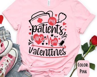May include: Pink t-shirt with a graphic design that says "My patients are my Valentines". The graphic includes a nurse's cap, a stethoscope, a heart beat line, and a syringe.