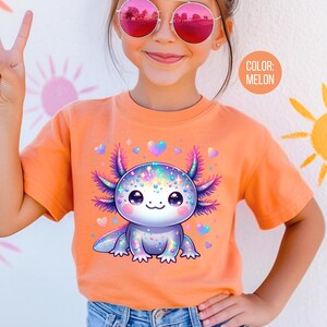 May include: A young person wearing a bright orange t-shirt with a colorful cartoon axolotl graphic. The axolotl is surrounded by hearts and sparkles. The text "COLOR: MELON" is visible in the upper right corner of the image.