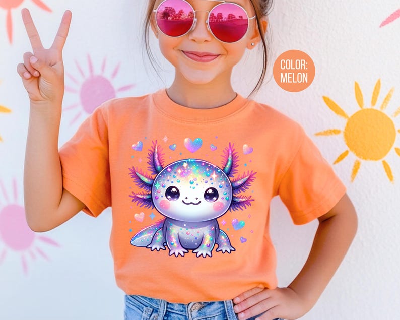 May include: A young person wearing a bright orange t-shirt with a colorful cartoon axolotl graphic. The axolotl is surrounded by hearts and sparkles. The text "COLOR: MELON" is visible in the upper right corner of the image.