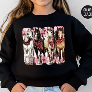May include: Black sweatshirt with a graphic of four horses wearing red bandanas and surrounded by hearts. The horses are white, black, tan, and brown. The background is pink. The text "COLOR: BLACK" is in a black circle.